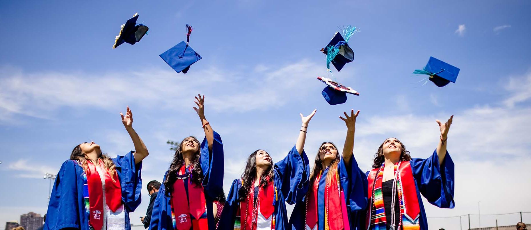 密歇根州立大学丹佛分校的毕业生将他们的帽子抛向空中.